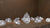 A large, brilliant pear cut diamond centered among several smaller loose diamonds on a warm brown surface.