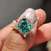 Yellow gold bridal set with an oval green moissanite ring and marquise open gap band.
