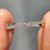 Crossover wedding band featuring round cut moissanite set in a modern curved design.