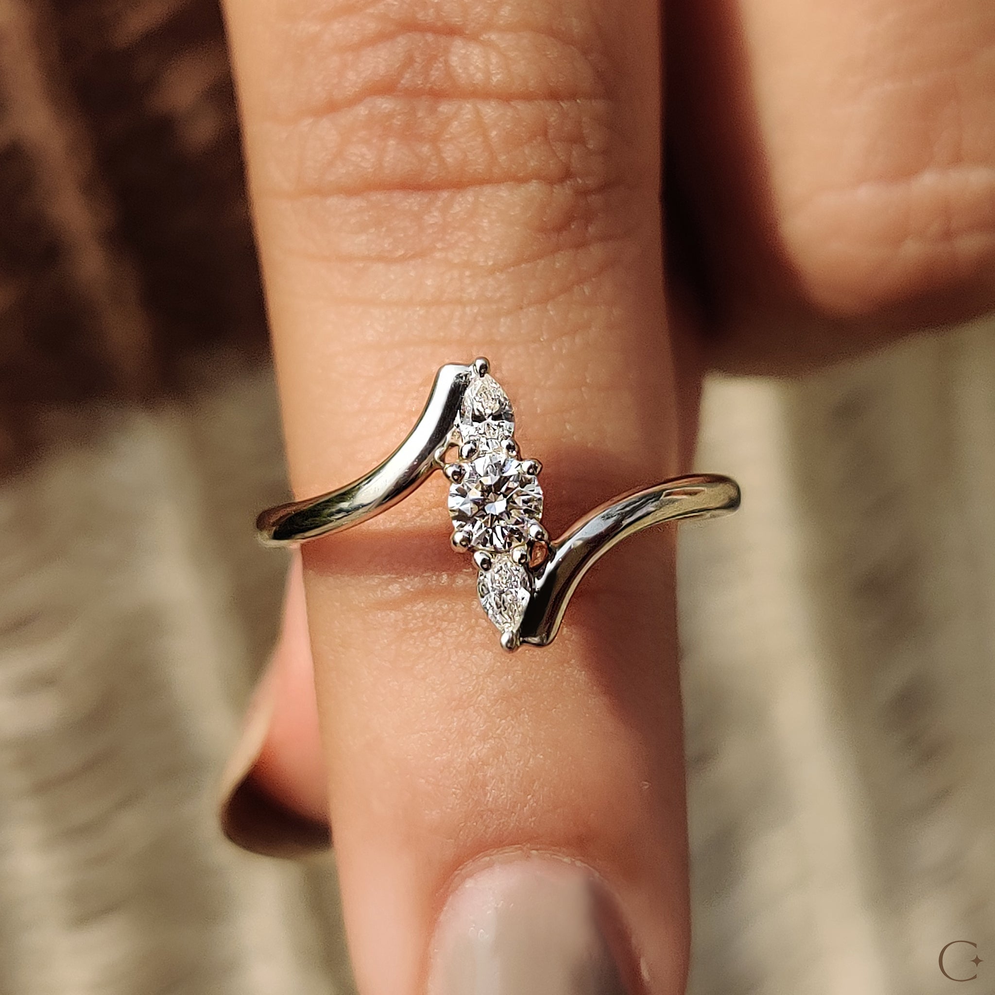 Three stone ring with round and pear diamonds.
