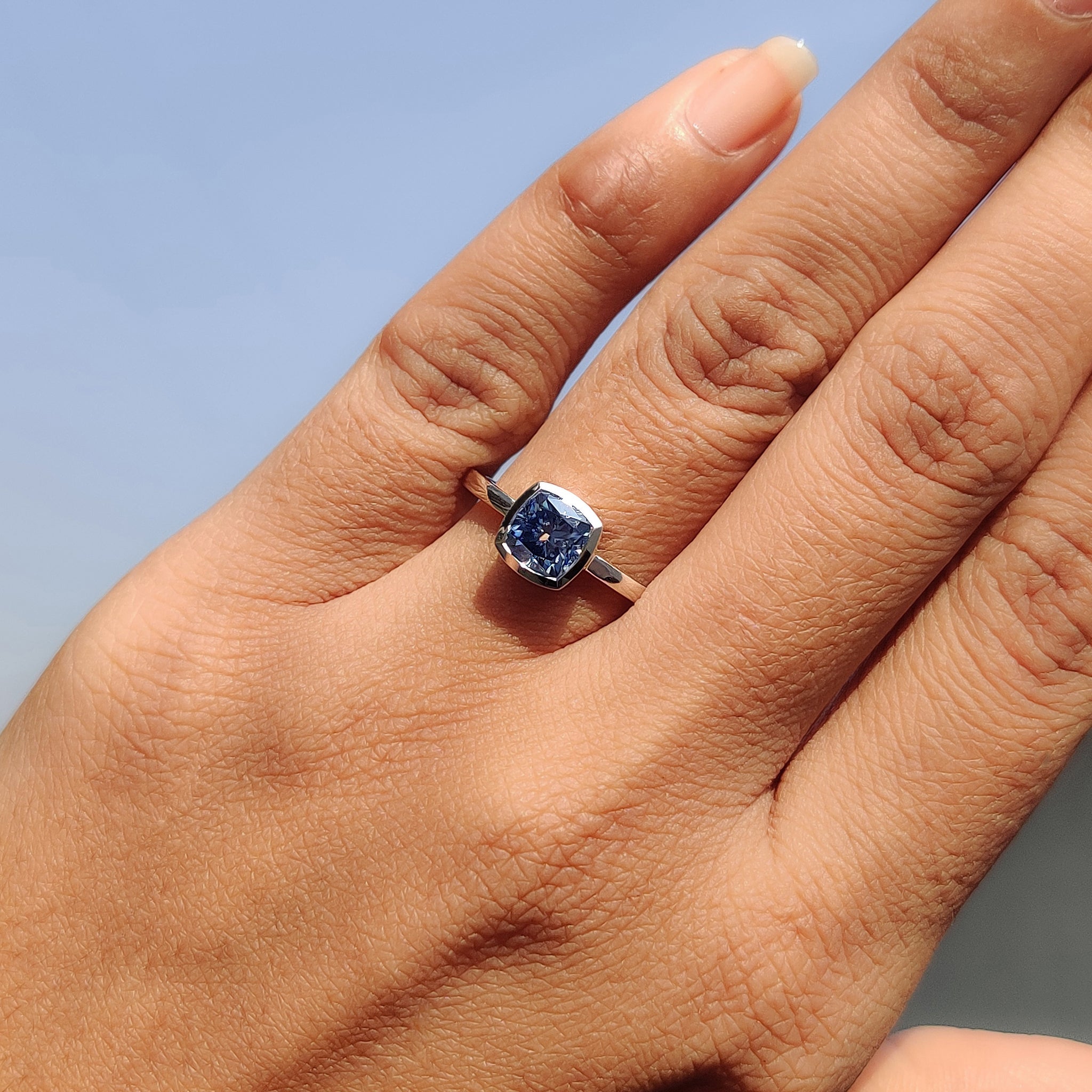 Bezel cushion cut engagement ring frames stones cleanly.
