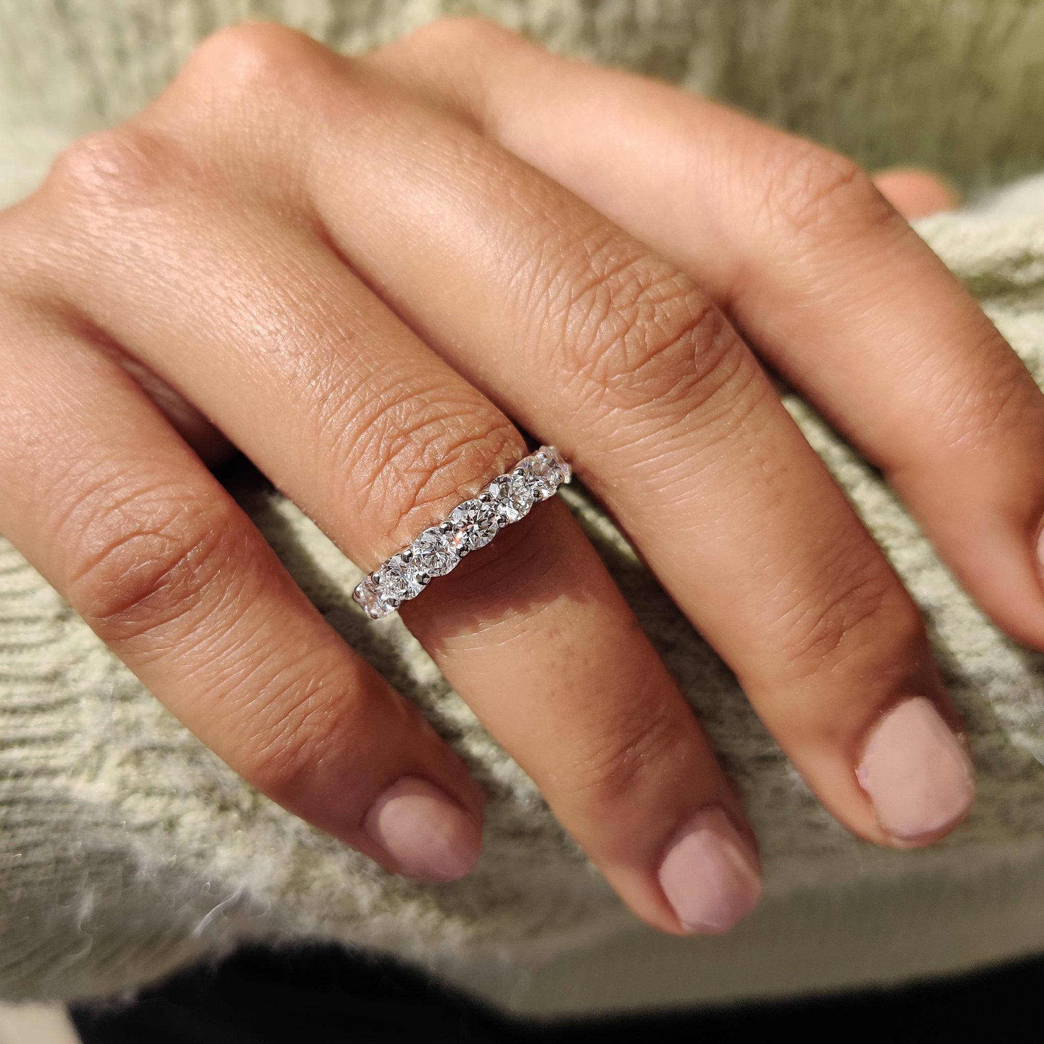 Round diamond eternity band displayed on a neutral ring holder.
