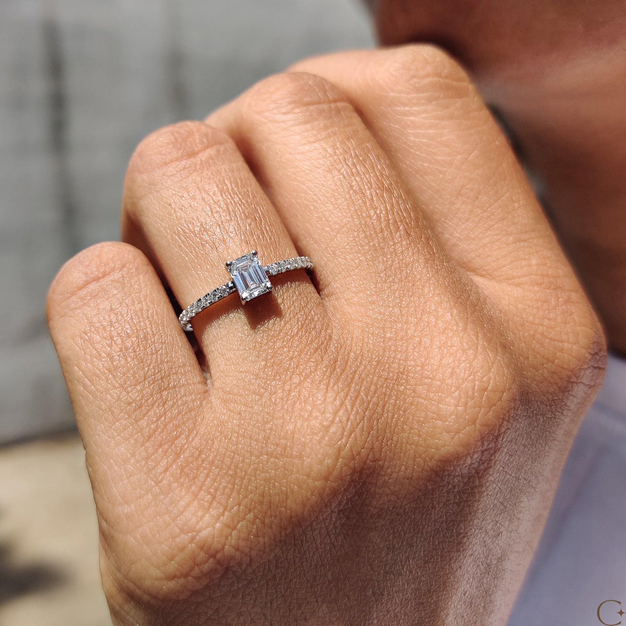 White gold engagement ring with emerald pave detailing.
