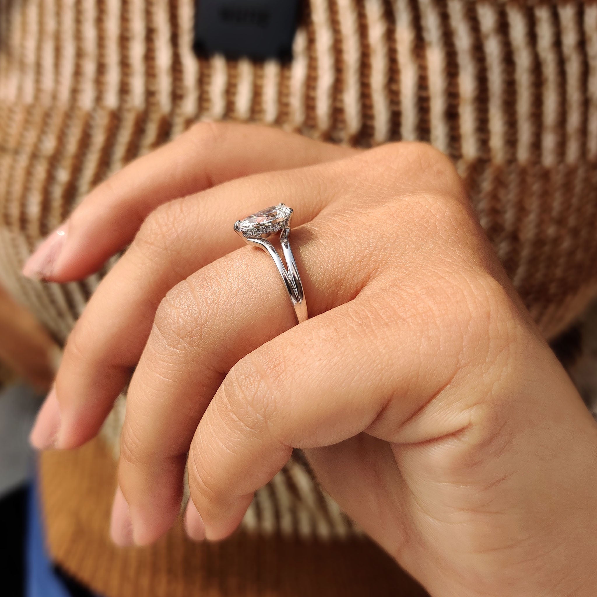 Hidden halo setting enhancing the beauty and shine of the pear-shaped diamond for an elegant look.
