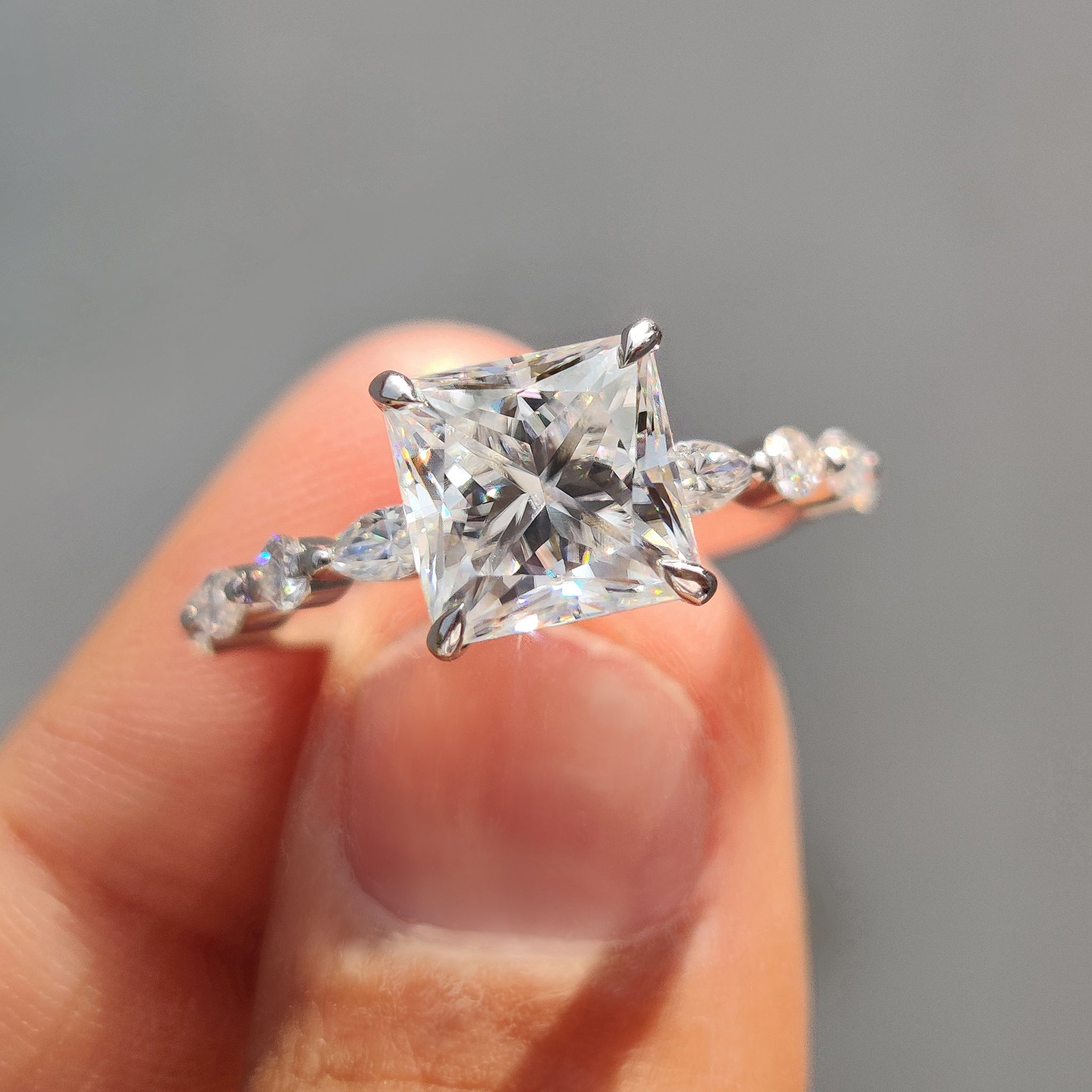 Princess cut moissanite ring shown in soft light.

