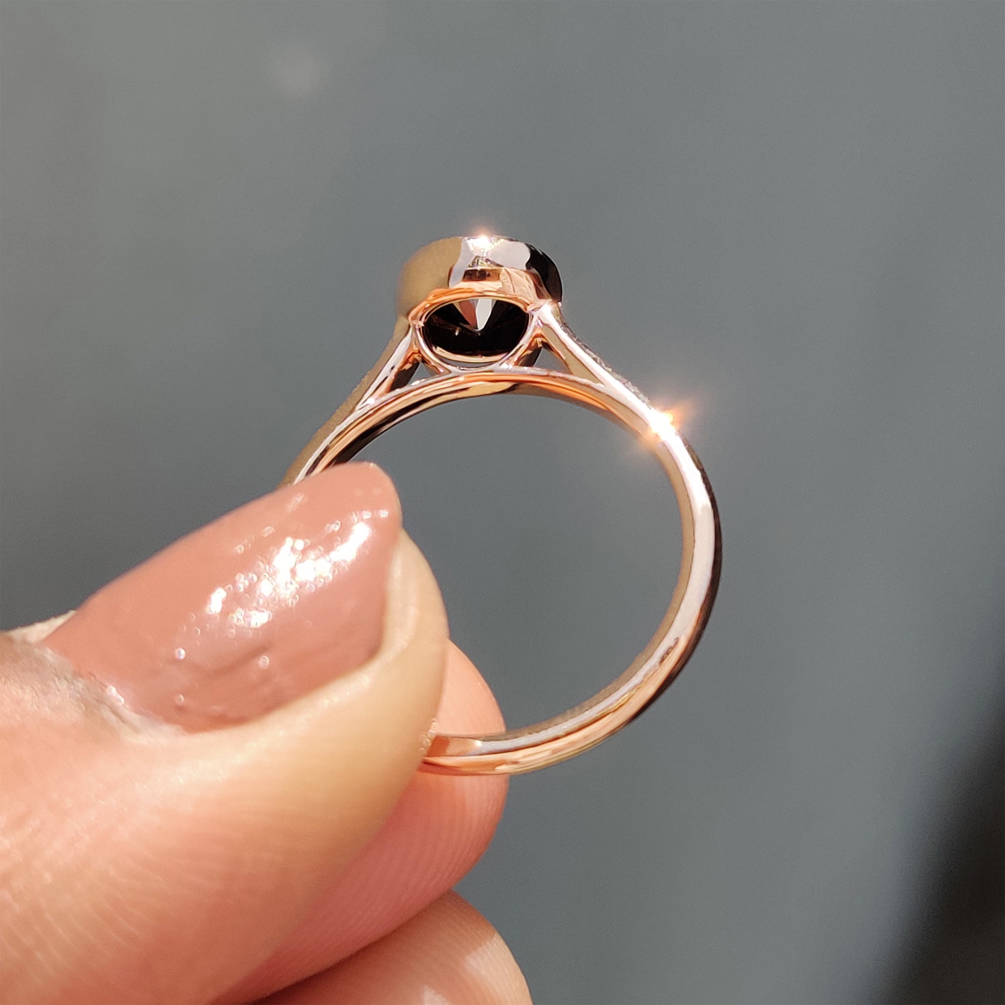 Rose gold engagement ring showcasing a black round cut Moissanite in a bezel setting.
