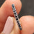 Black stone wedding band with prong set moissanite in a half eternity style.