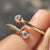 Two stone wedding band featuring round cut moissanite in a modern open gap design.
