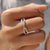 Crossover wedding band features a round moissanite wedding band.