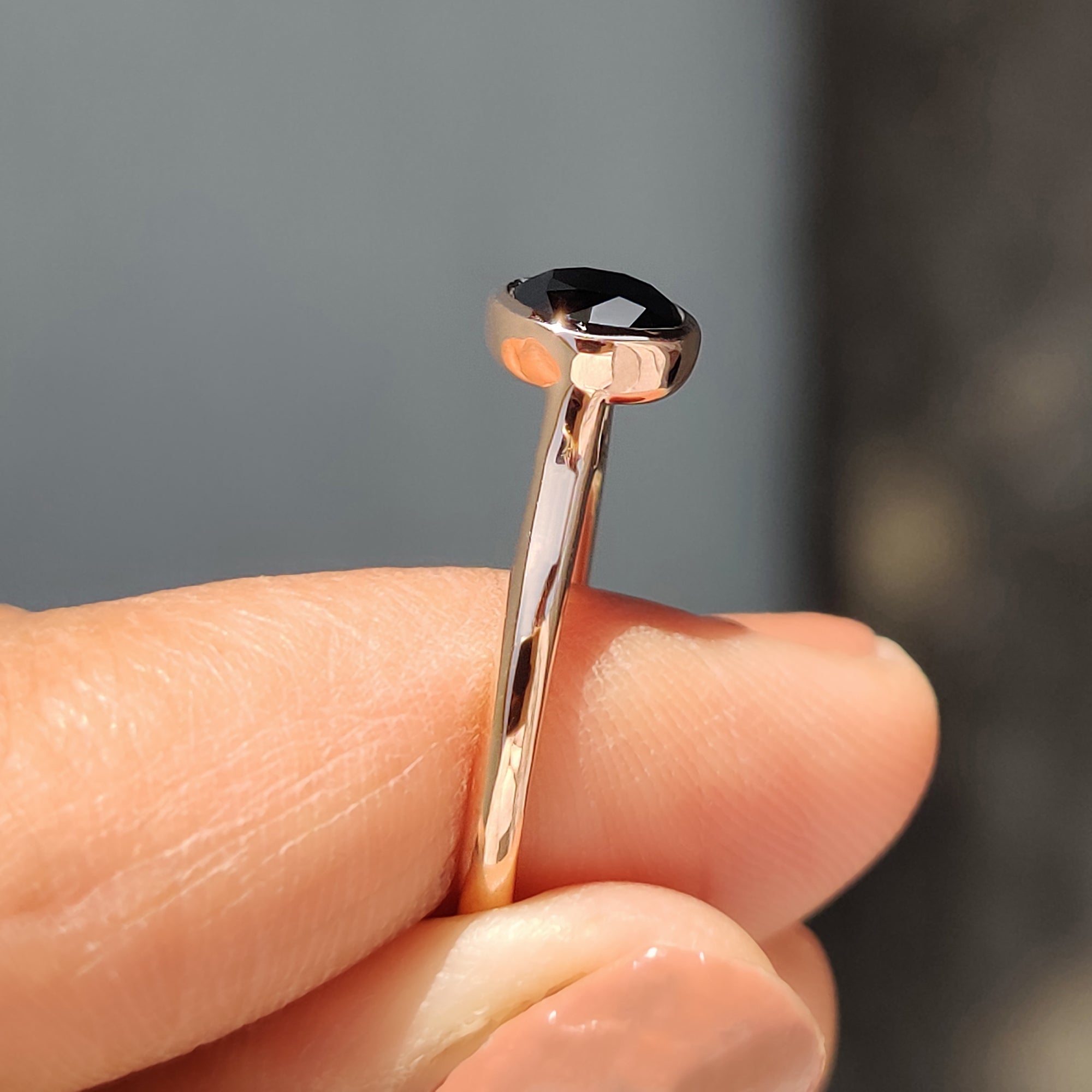 Moissanite engagement ring in rose gold with a cathedral setting and bold black stone.
