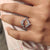 Moissanite wedding band with pear and round cuts in a wrap guard enhancer shape.
