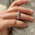 Round diamond wedding band worn on a bride's finger.
