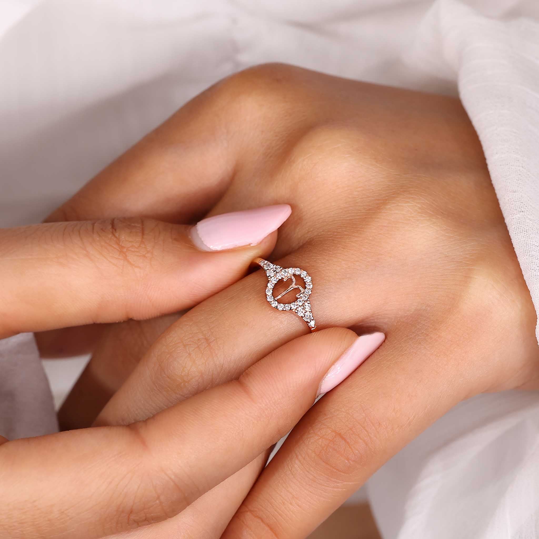 Aries gold ring with halo diamond and round side stone detailing.
