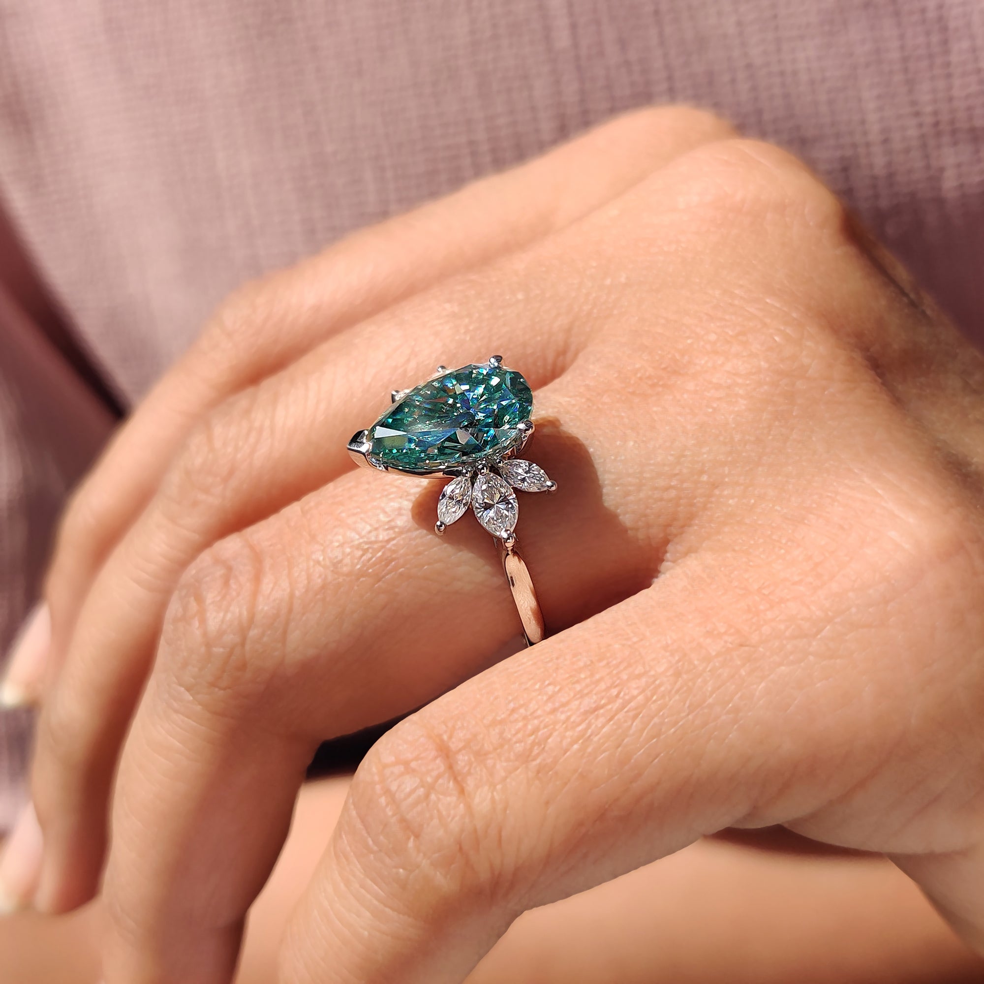 V prong setting with pear cyan blue stone and marquise cut side stones for a custom engagement ring.
