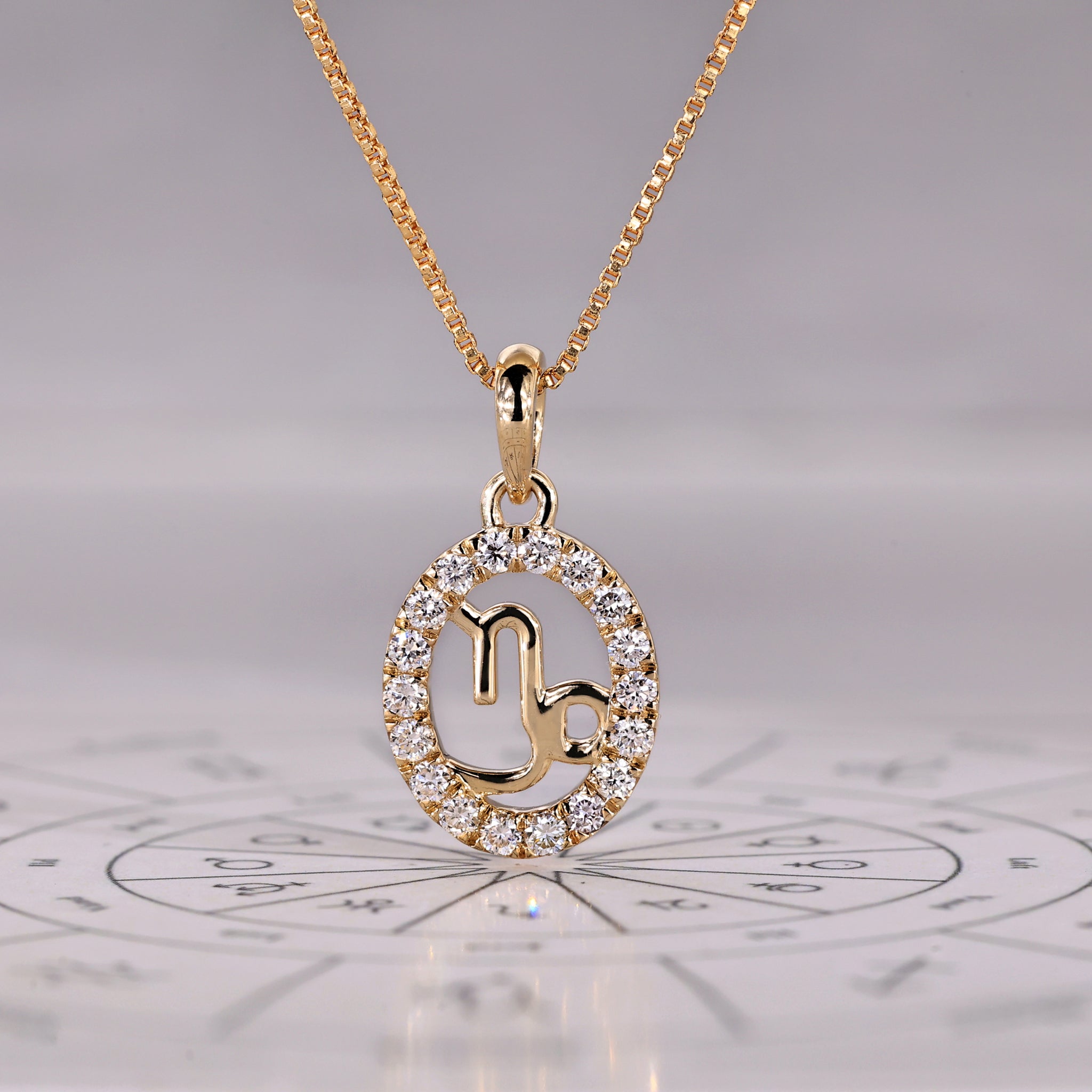 Capricorn pendant in yellow gold features a halo diamond design and zodiac motif.
