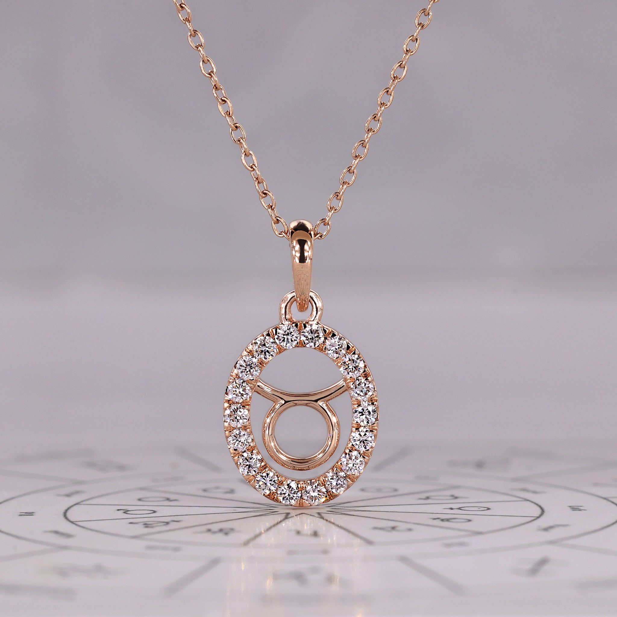 Rose gold Taurus pendant with halo diamond and round cut design.