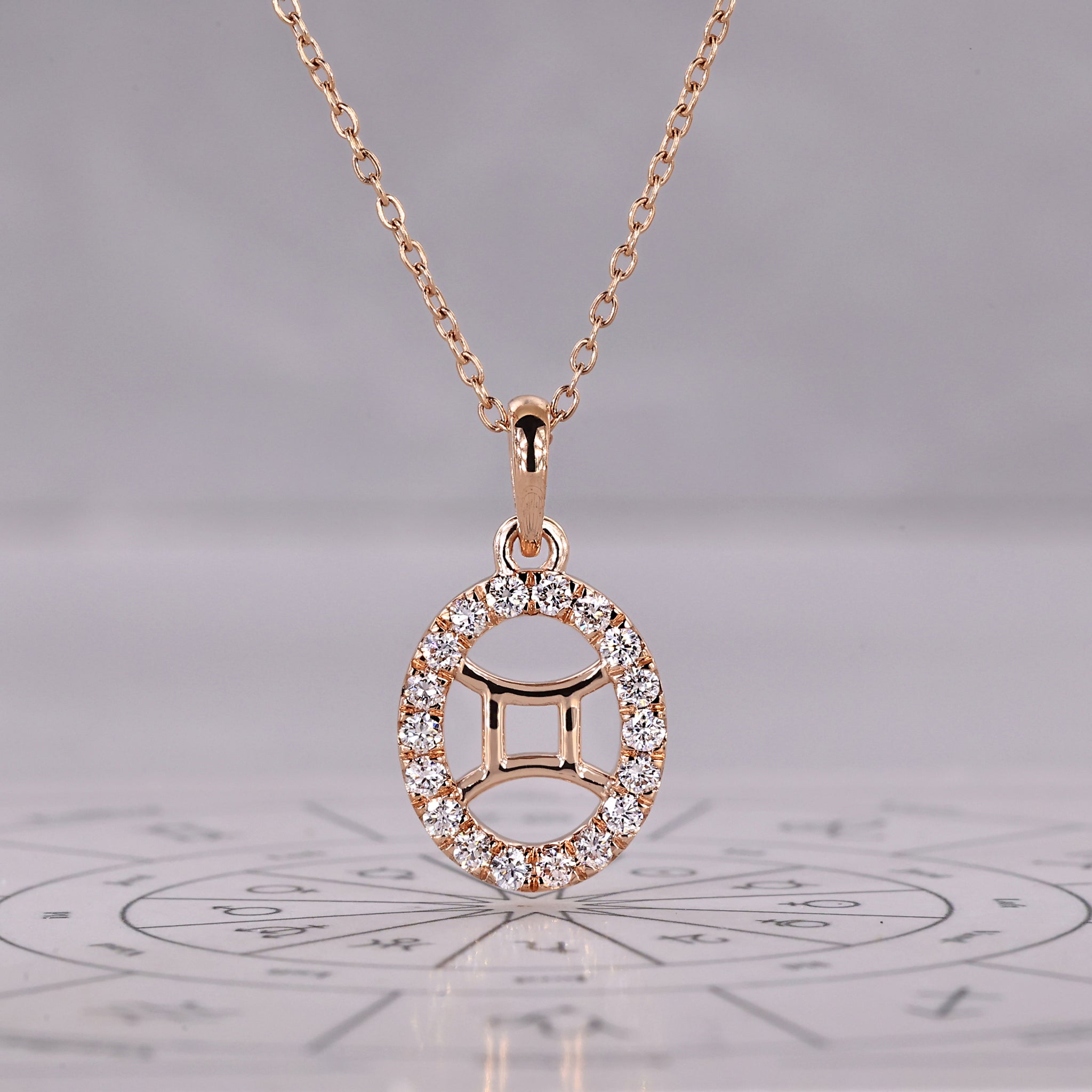 Gold Gemini pendant with halo diamond and round cut design.