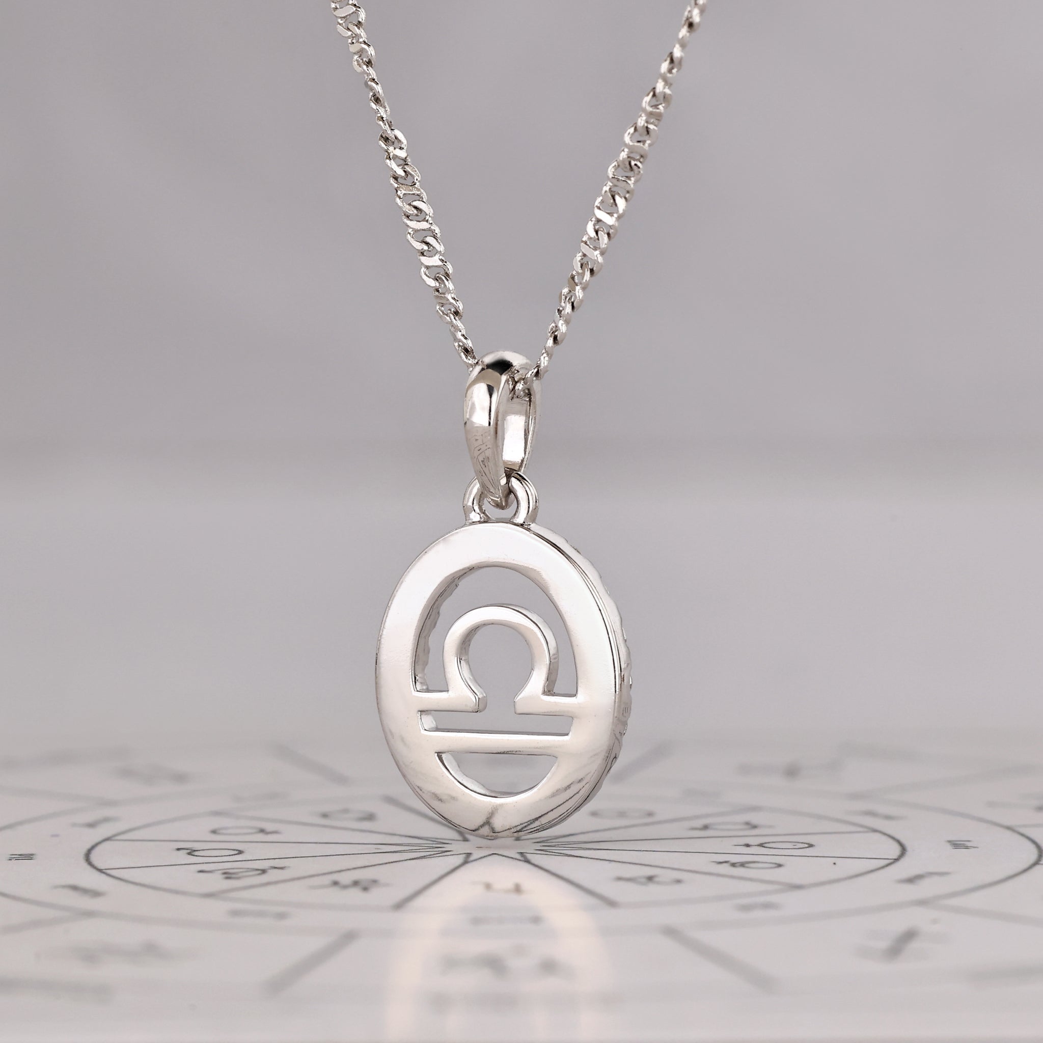 Lab-grown diamonds enhance the halo setting of this Libra pendant.