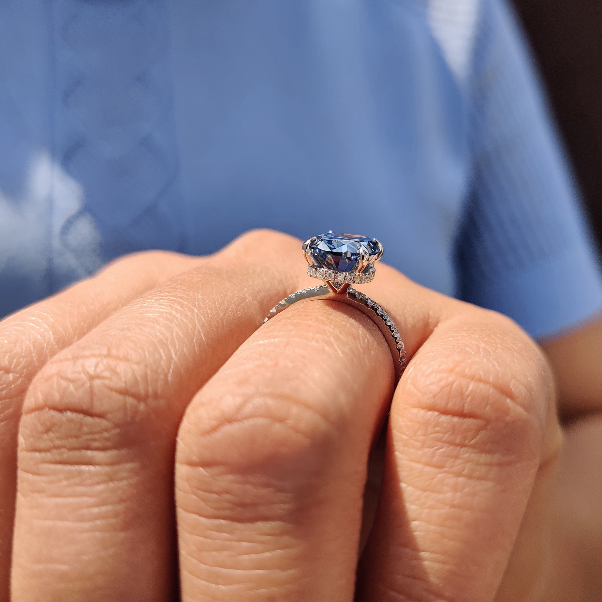 Unique engagement ring with royal dark blue oval cut Moissanite and a round cut hidden halo setting.
