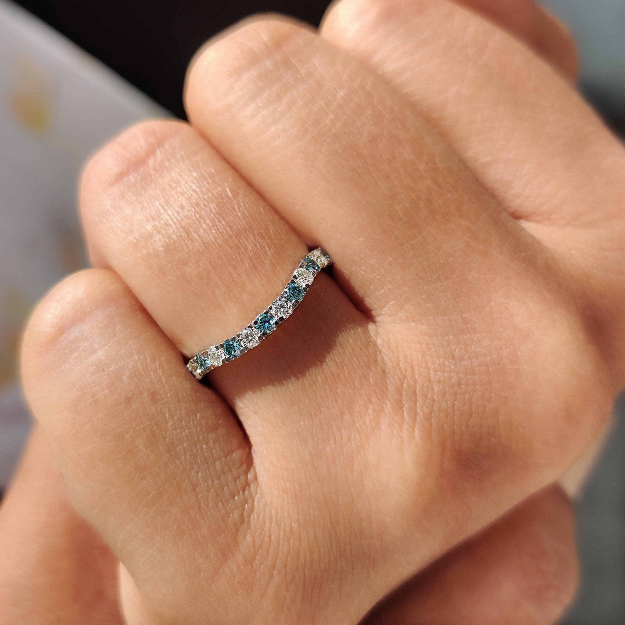 Curved wedding band with a subtle design and cyan blue stone accent.