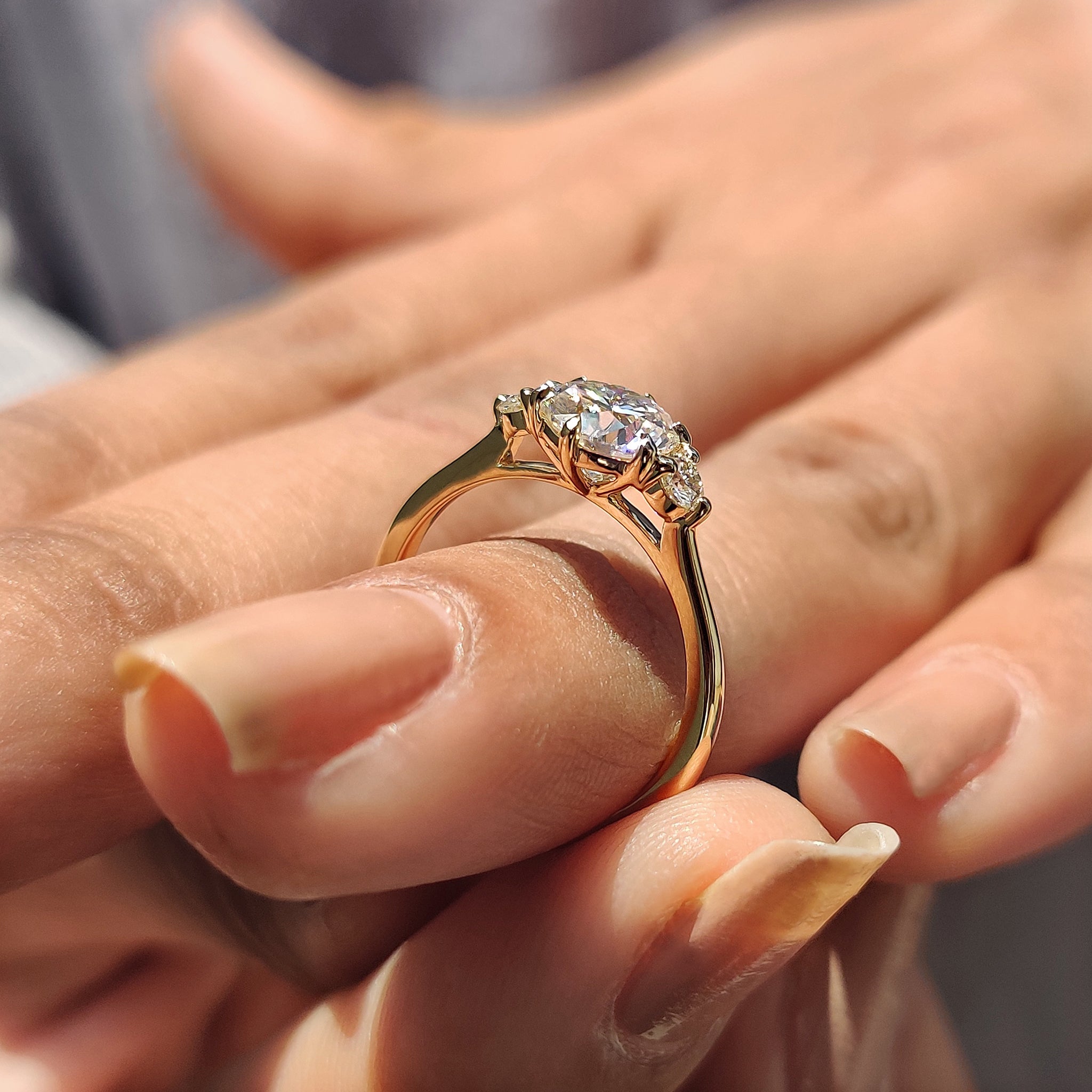 Handmade jewelry piece with a round cut Moissanite in a unique three stone design.