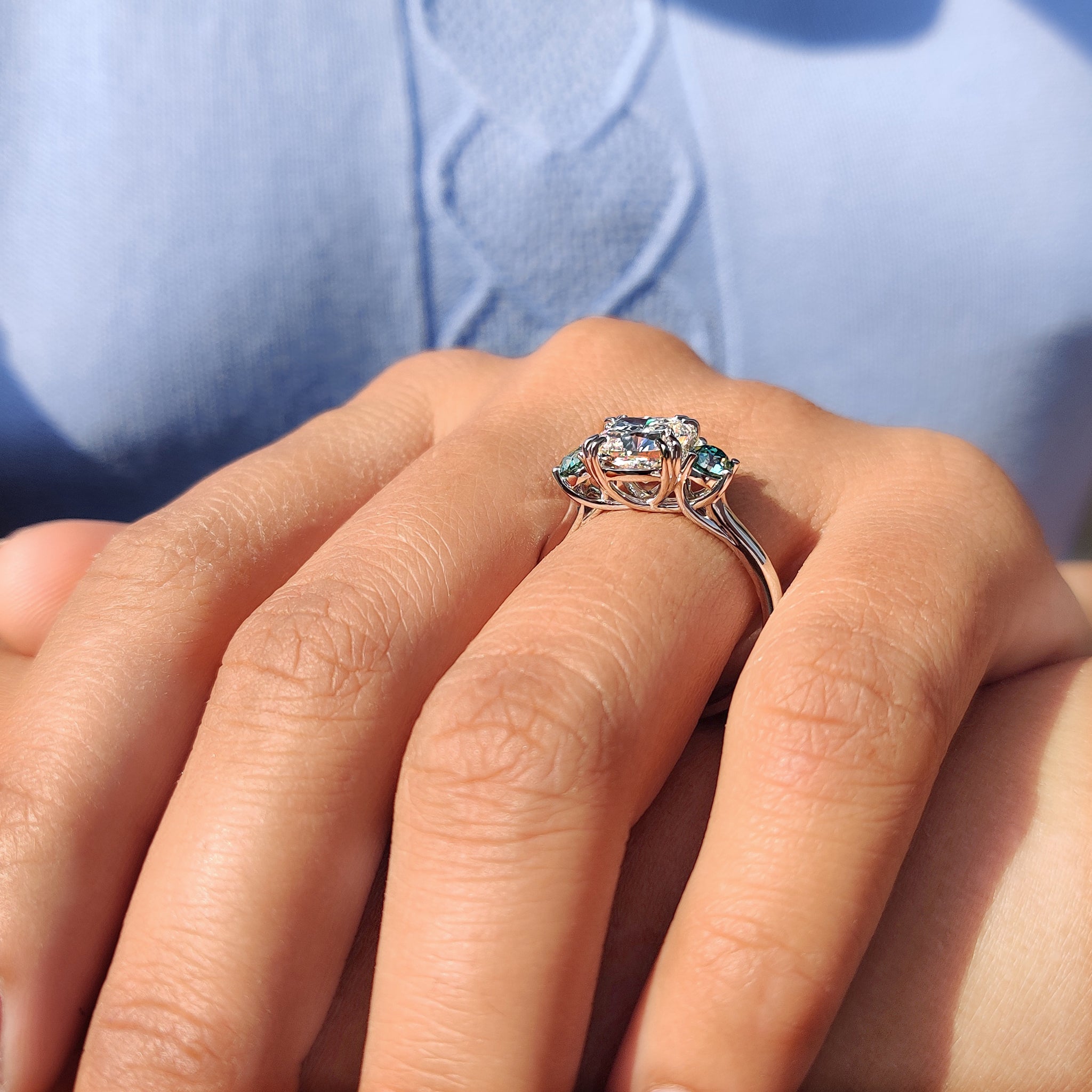 Cushion Moissanite ring with two green side stones.