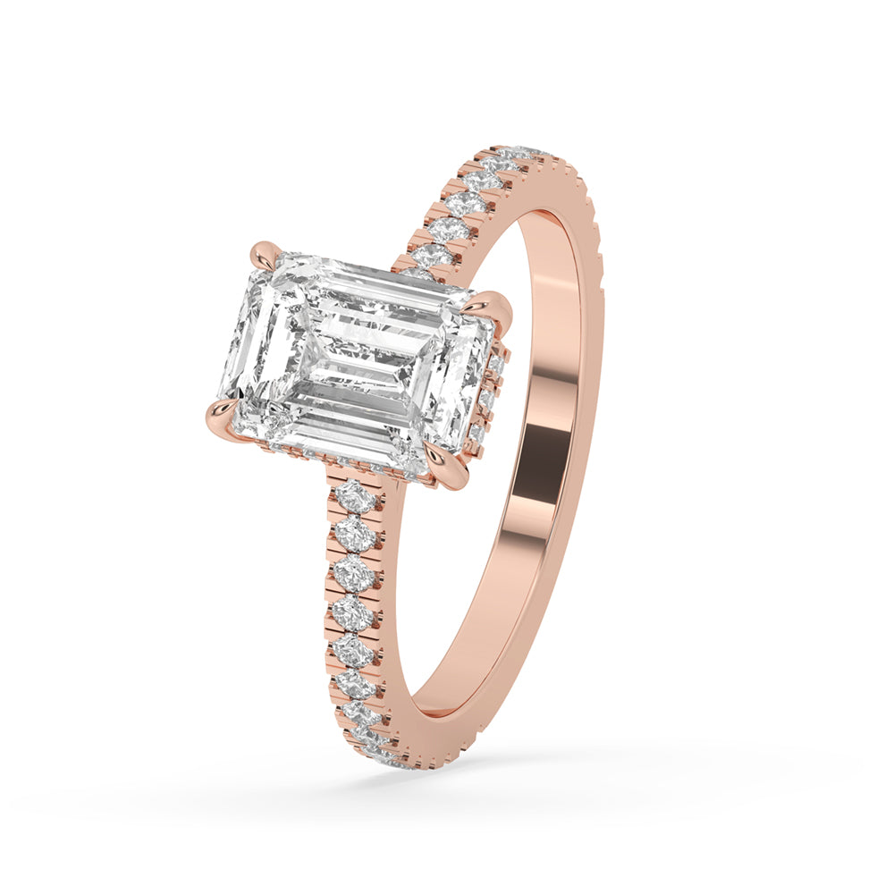Classic emerald diamond ring set in a hidden halo setting, with a cathedral style engagement ring featuring a pave engagement ring design.
