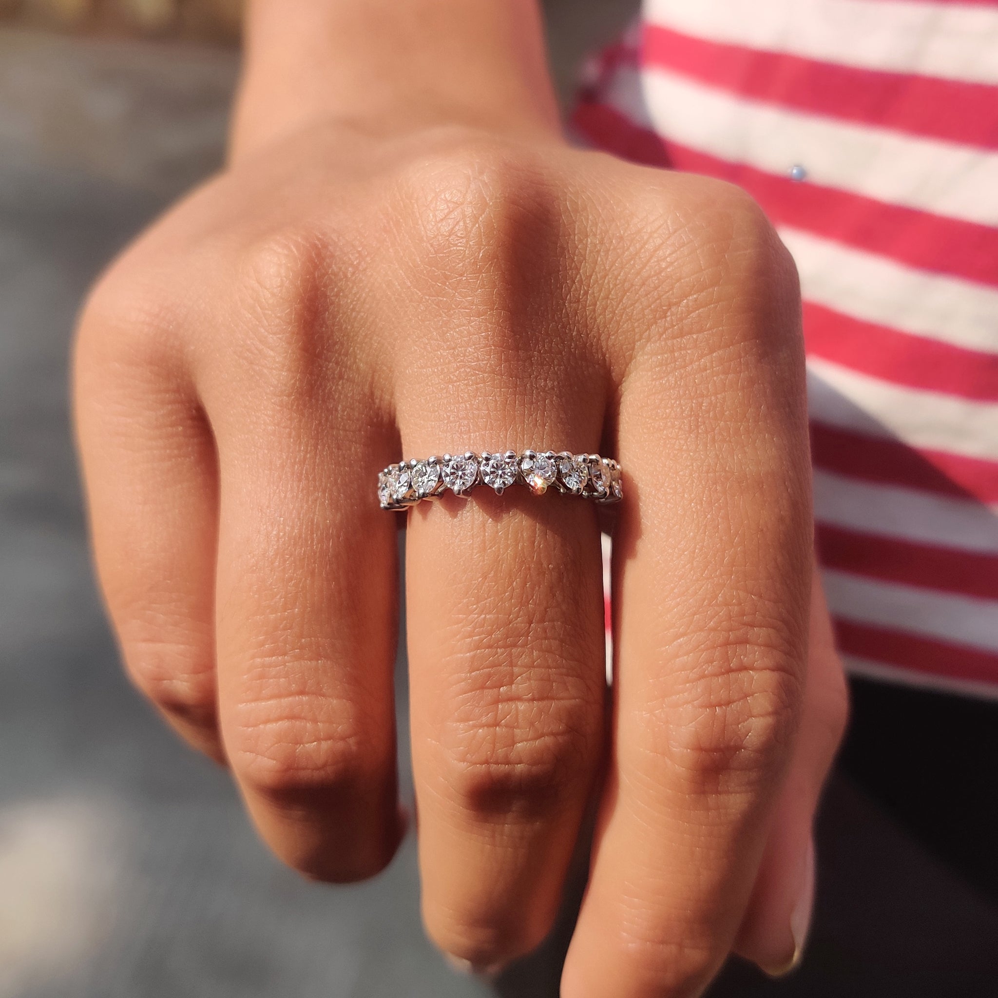 Three prong setting wedding band showcasing round moissanite stones in an airy, elegant layout.