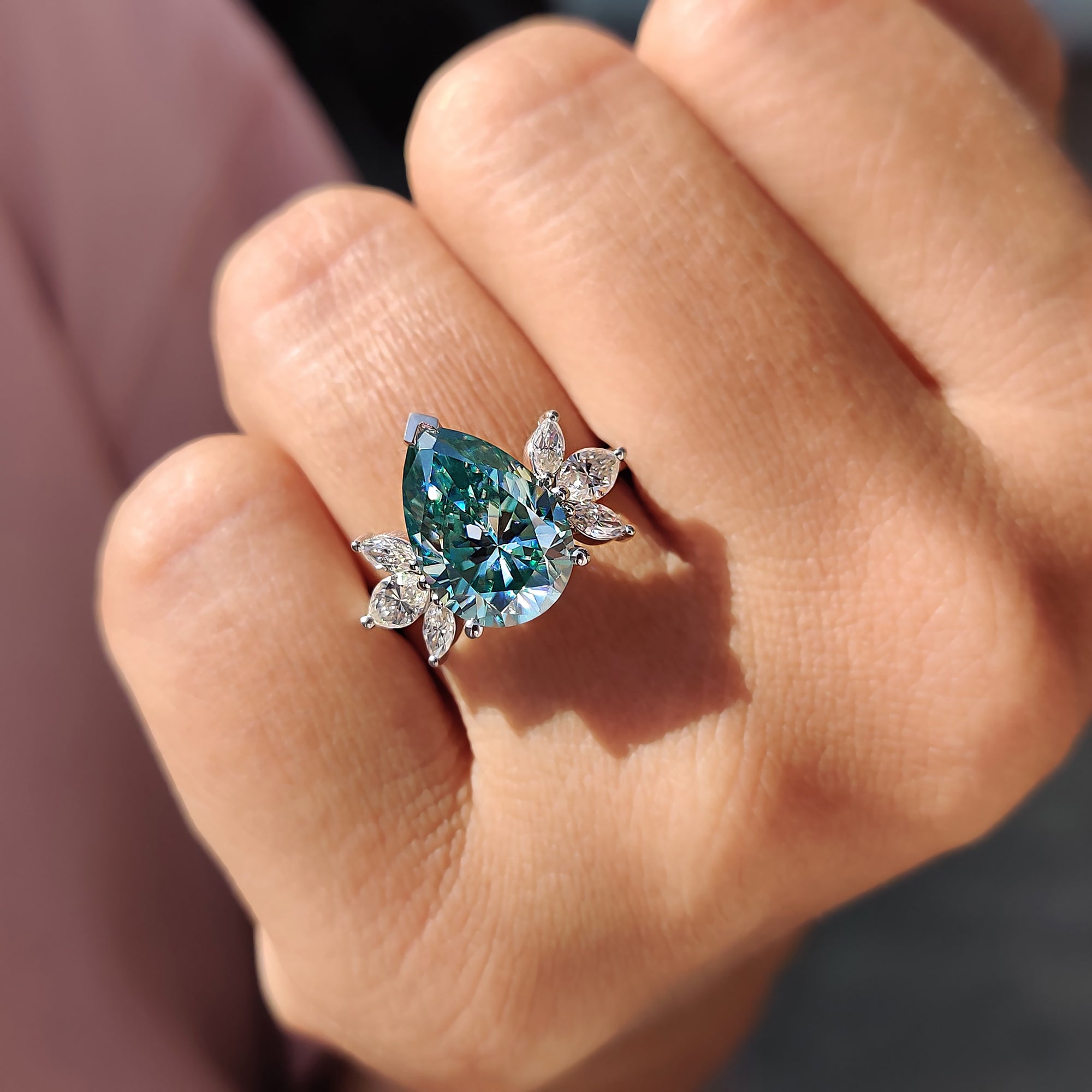 Unique engagement ring crafted with marquise cut side stones and a bold pear cyan blue centre.
