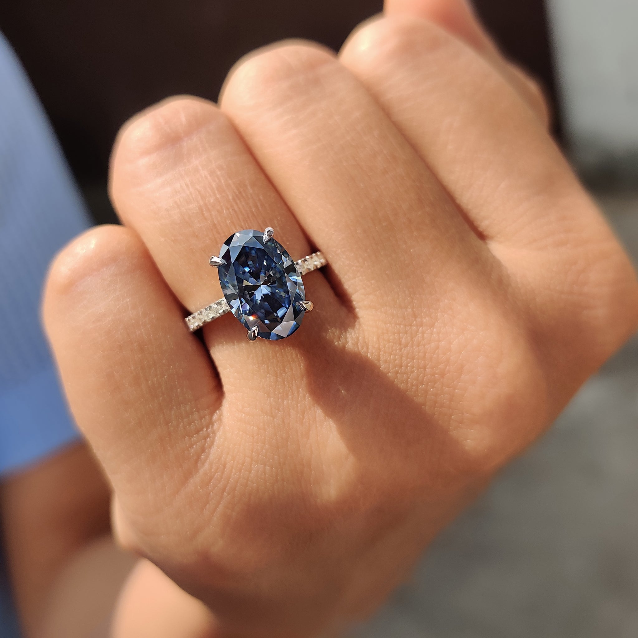 Moissanite engagement ring featuring oval cut royal dark blue Moissanite and a round cut pave band.
