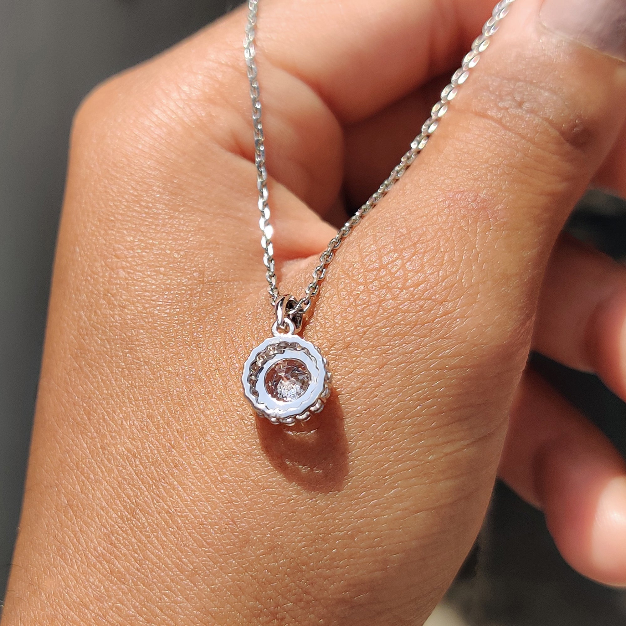 White gold diamond pendant featuring a round diamond halo.
