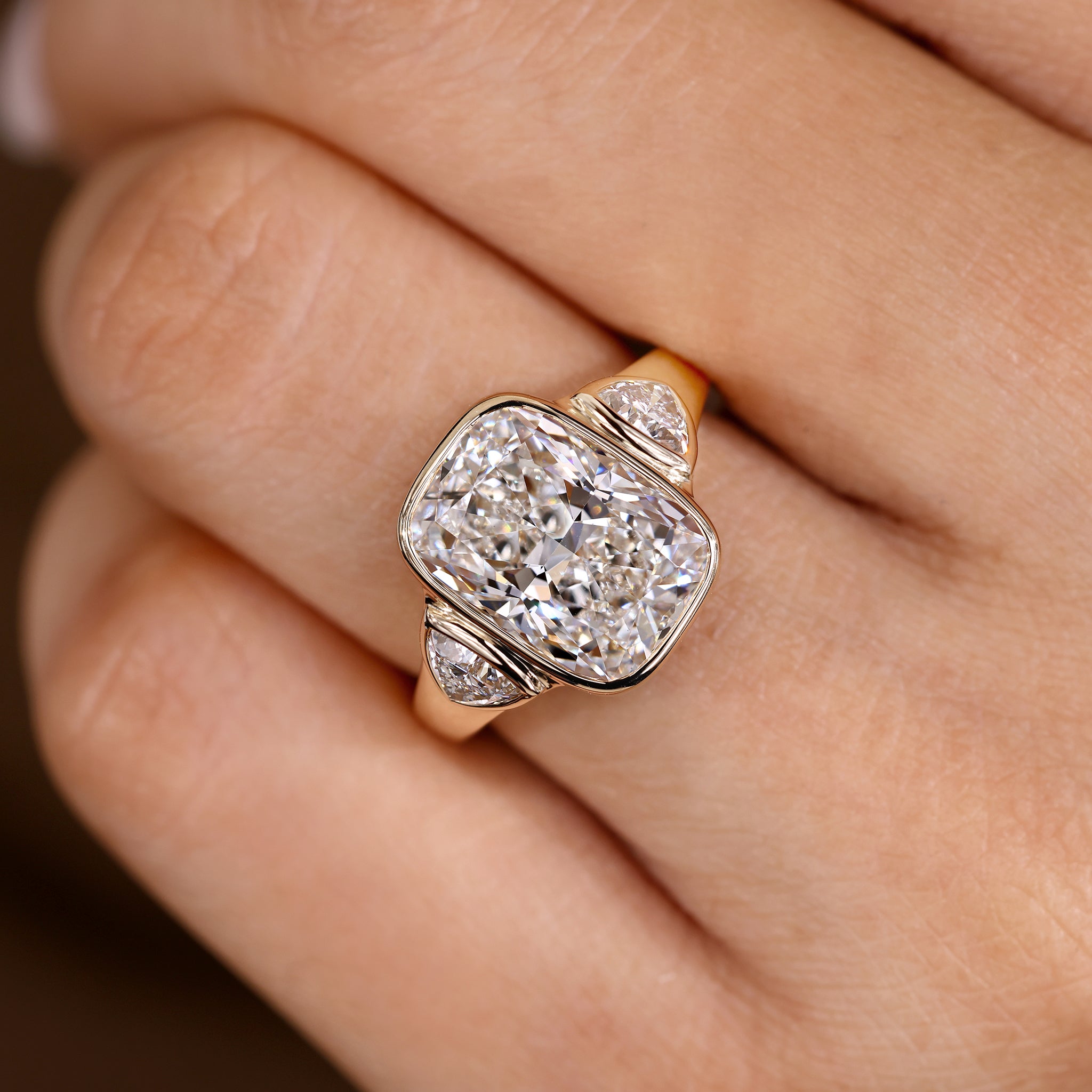 Elongated cushion cut ring with bezel setting and cathedral design
