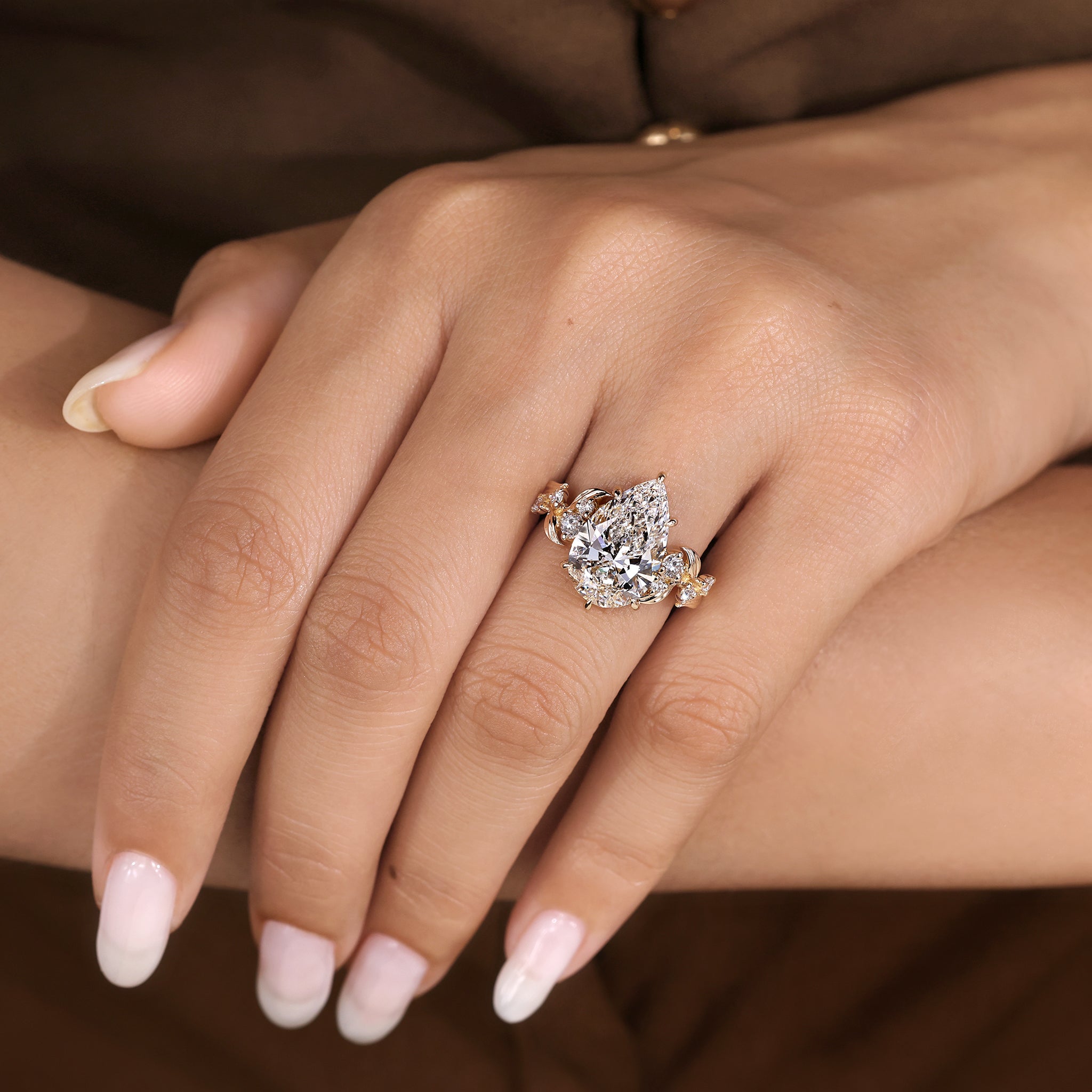 Pear shaped diamond ring with nature inspired details and round side stones
