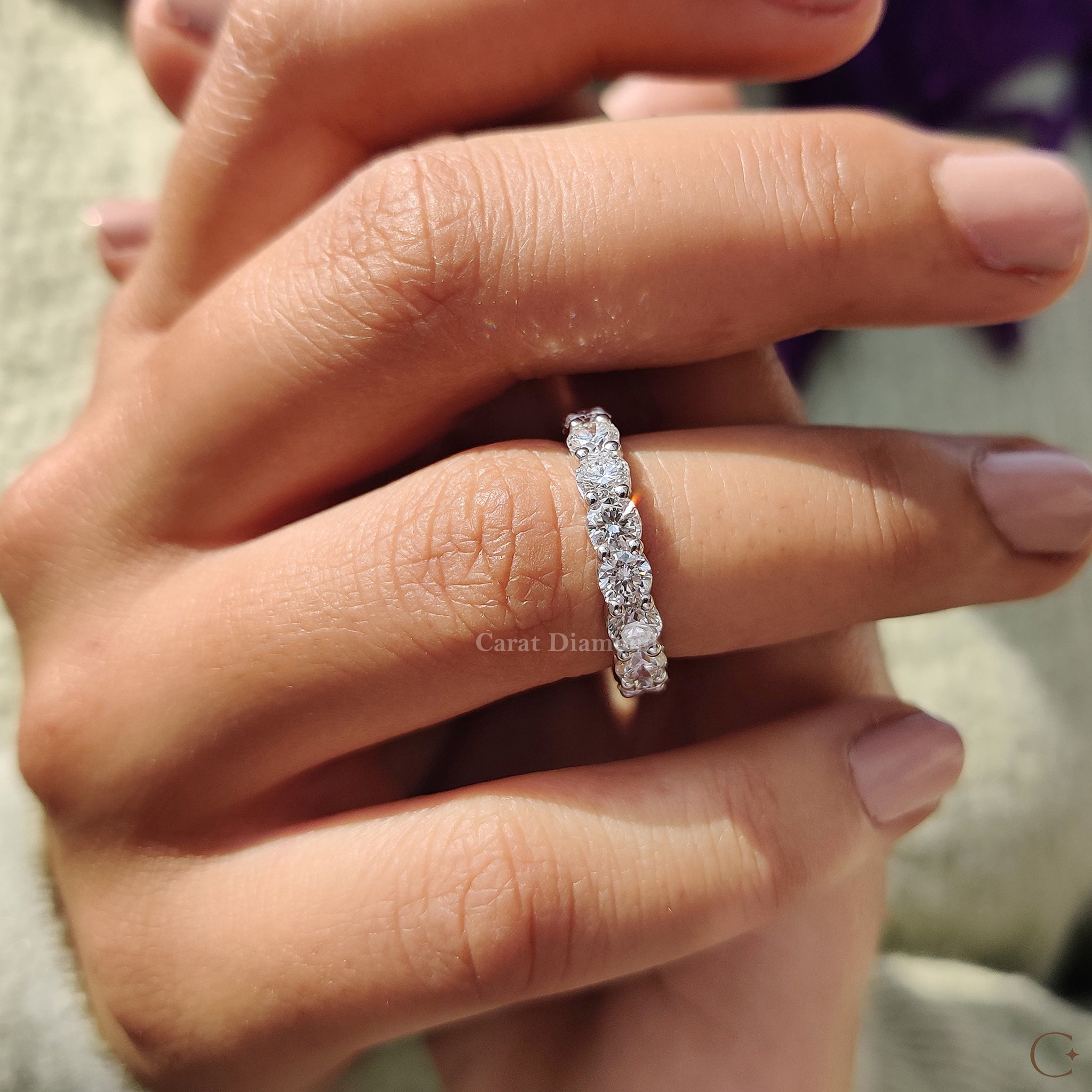White gold diamond band resting on a soft fabric background.
