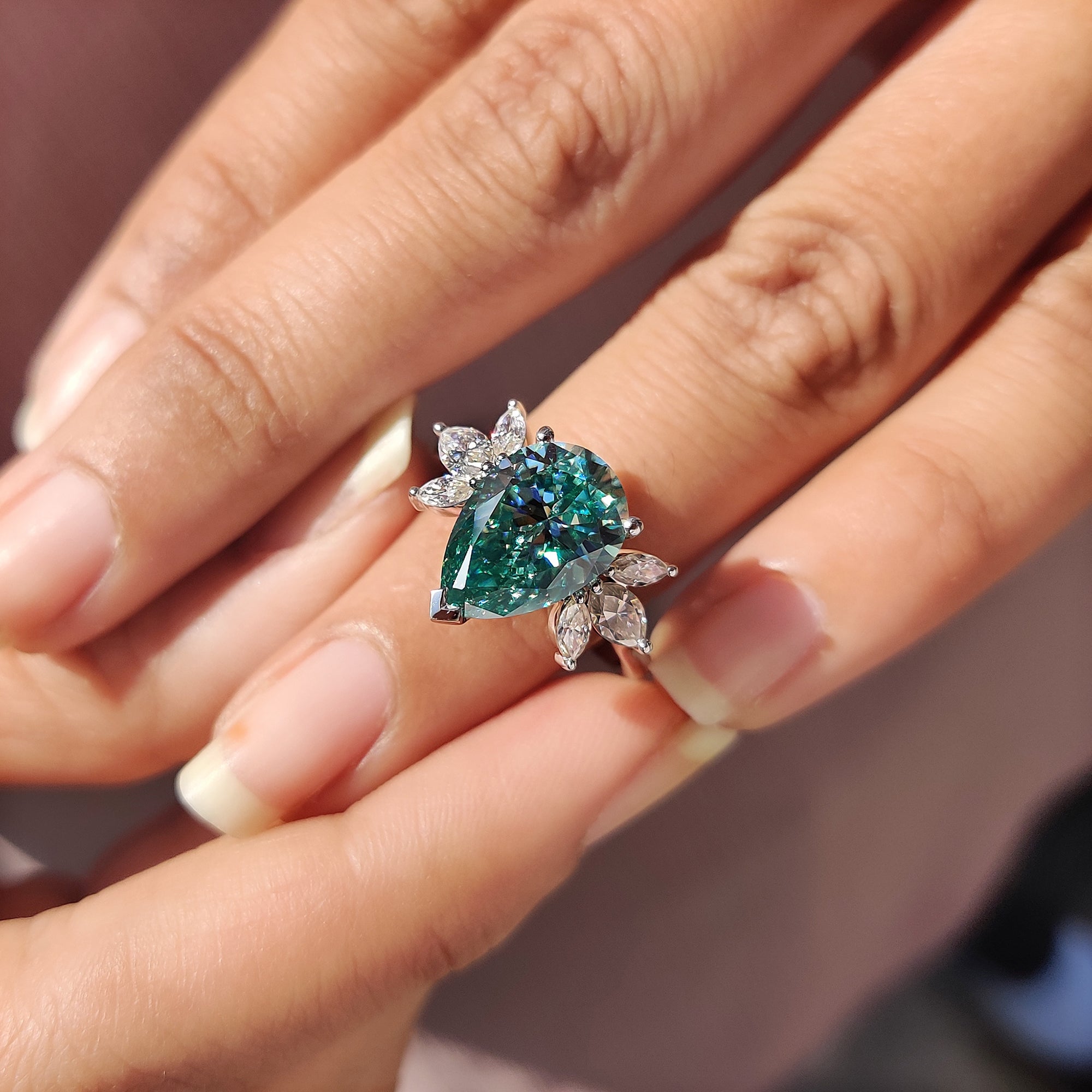 Women’s anniversary ring with a white gold band and bright cyan blue Moissanite centre stone.
