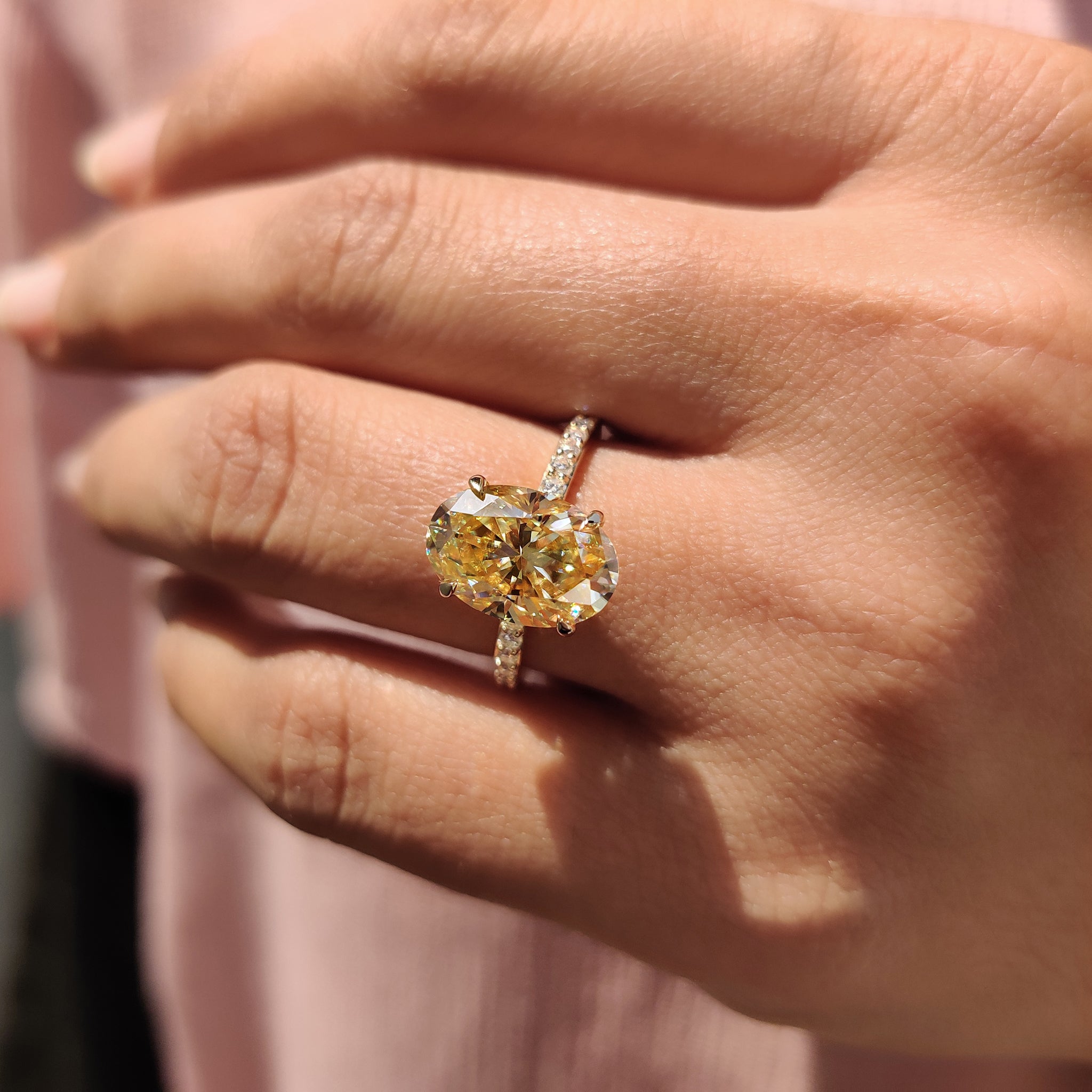 4 claw prong setting holds a yellow oval cut Moissanite, creating a beautiful engagement ring.