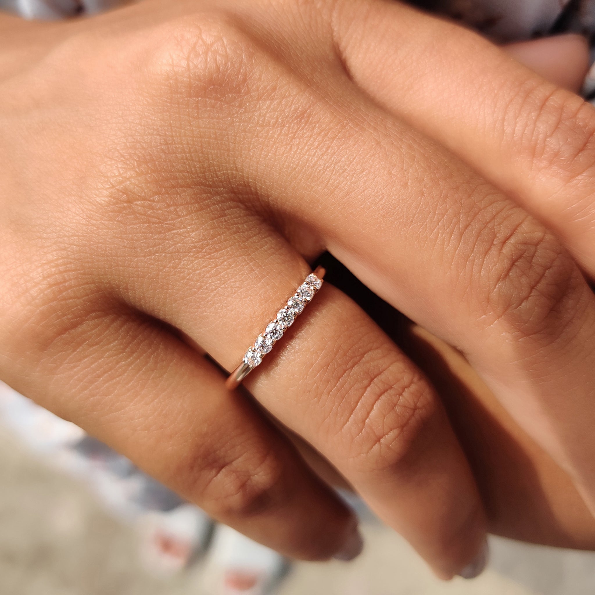 Custom wedding band featuring round moissanite stones and a sleek rose gold band.