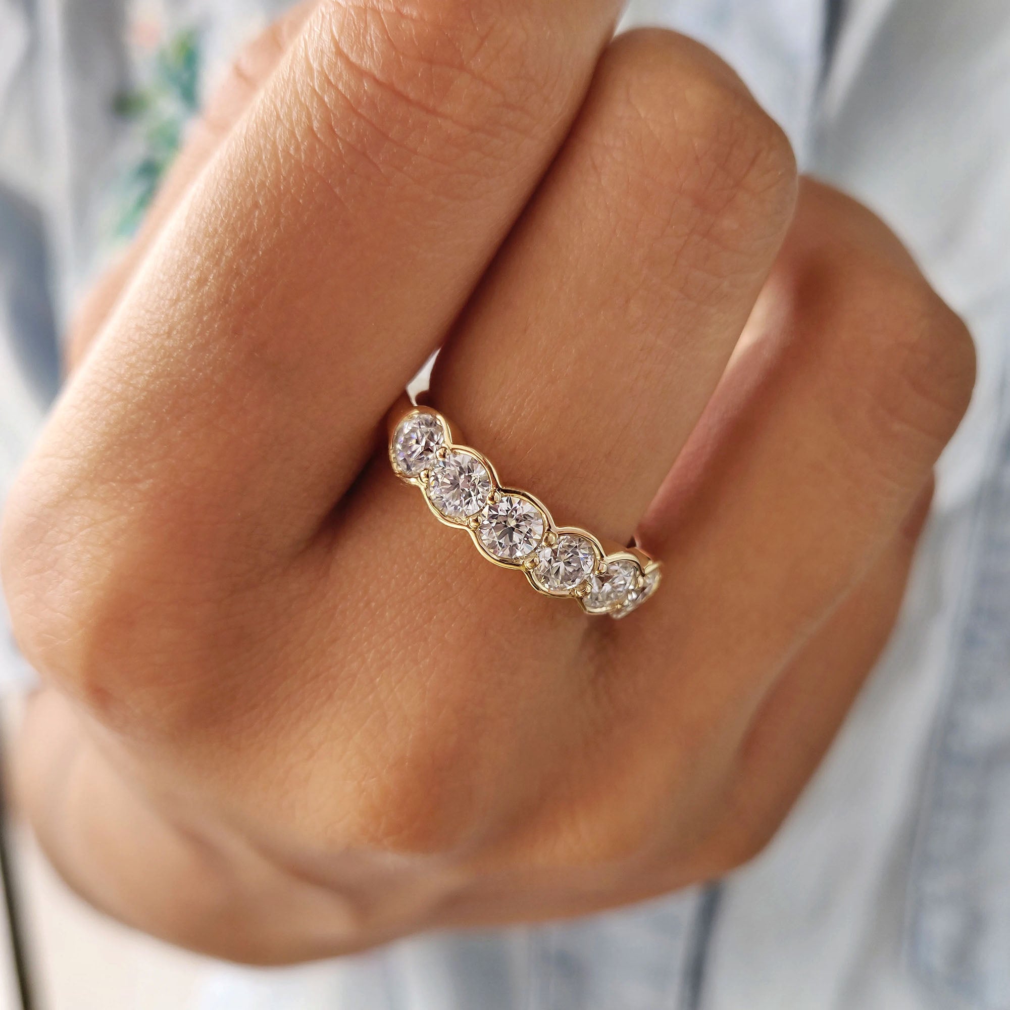 6 stone wedding band crafted from yellow gold and round moissanite.
