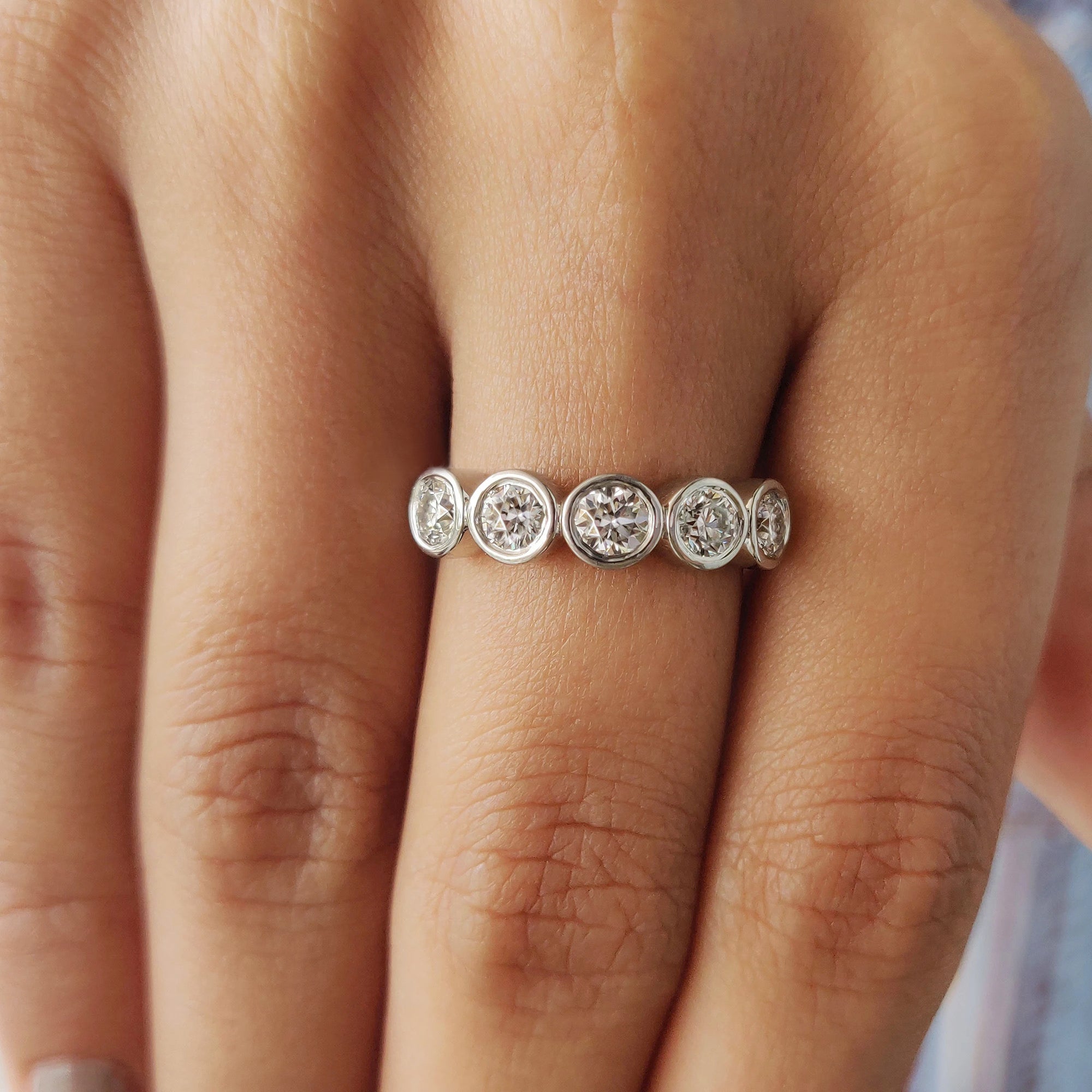 Bezel set moissanite band crafted in white gold.
