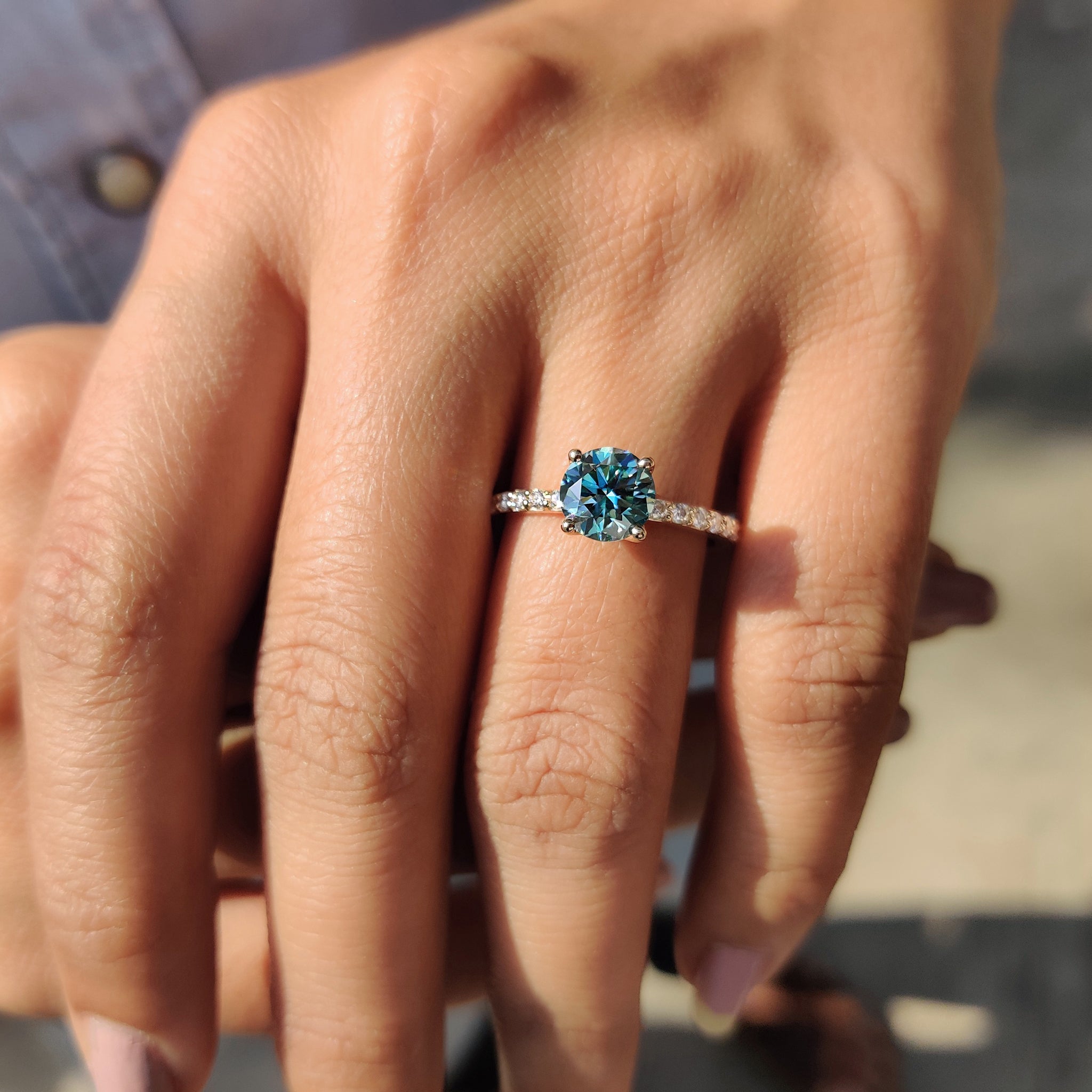 A yellow gold ring shines beautifully with a cyan blue round cut moissanite ring at the centre.
