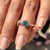Stunning cyan blue round cut Moissanite solitaire engagement ring in a 6 prong setting

