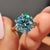 Round cut solitaire ring set with cyan blue moissanite for bold color.
