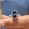 Oval hidden halo engagement ring featuring royal dark blue oval cut Moissanite in a 4 claw prong setting.
