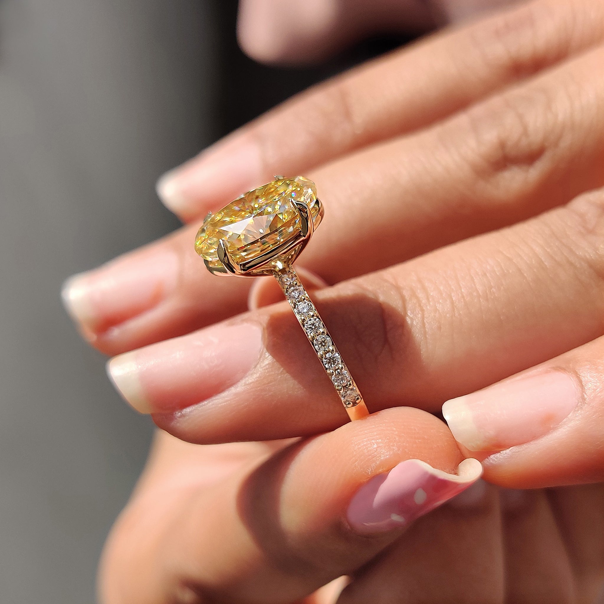 Moissanite engagement ring in yellow gold, featuring a large oval cut stone and round side stones.