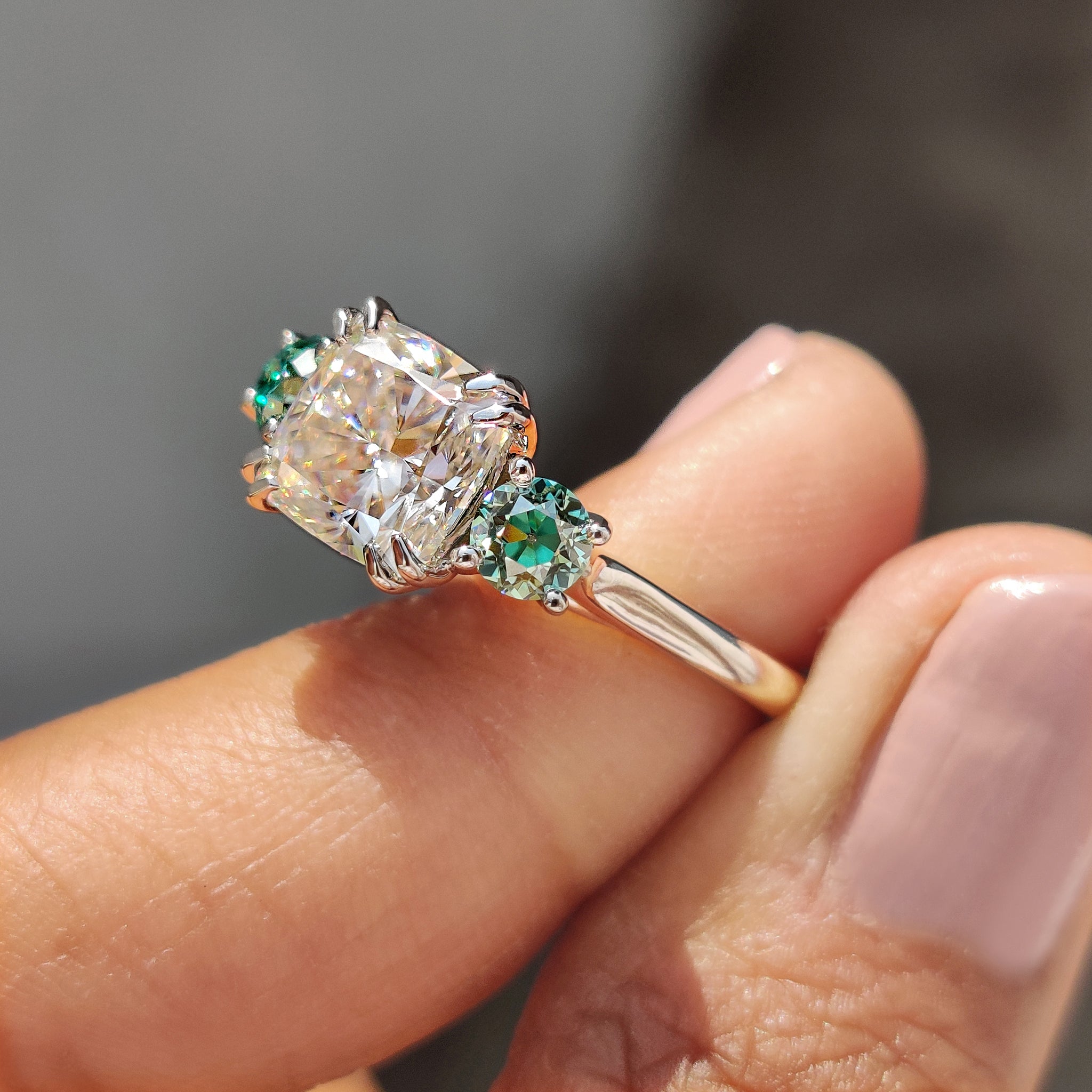 Handmade white gold engagement ring with green side stones.