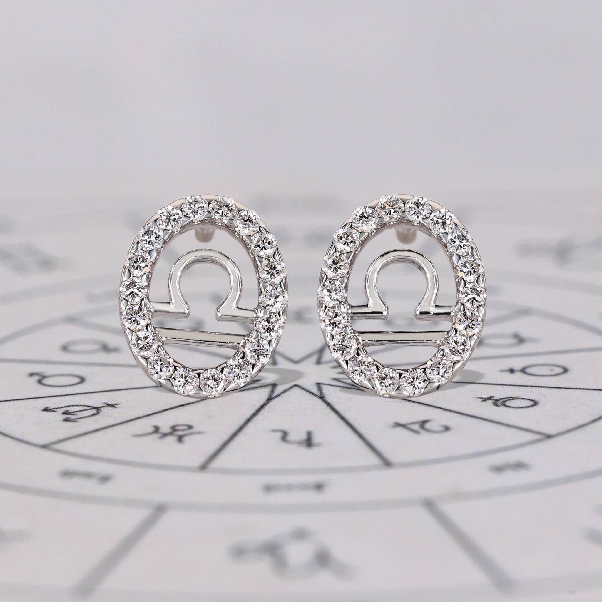 Libra earrings in white gold with round diamond halo studs.
