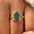 Yellow gold cluster ring with a green hexagon step cut center diamond.

