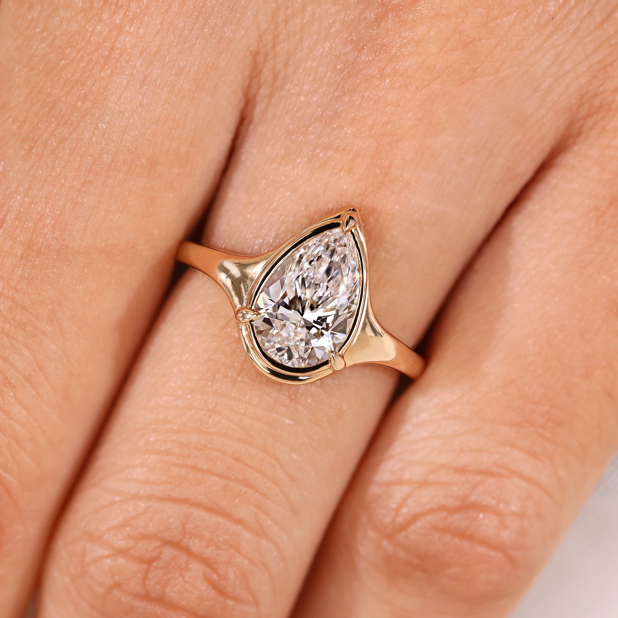 Pear cut diamond ring with bezel solitaire and tapered shank.
