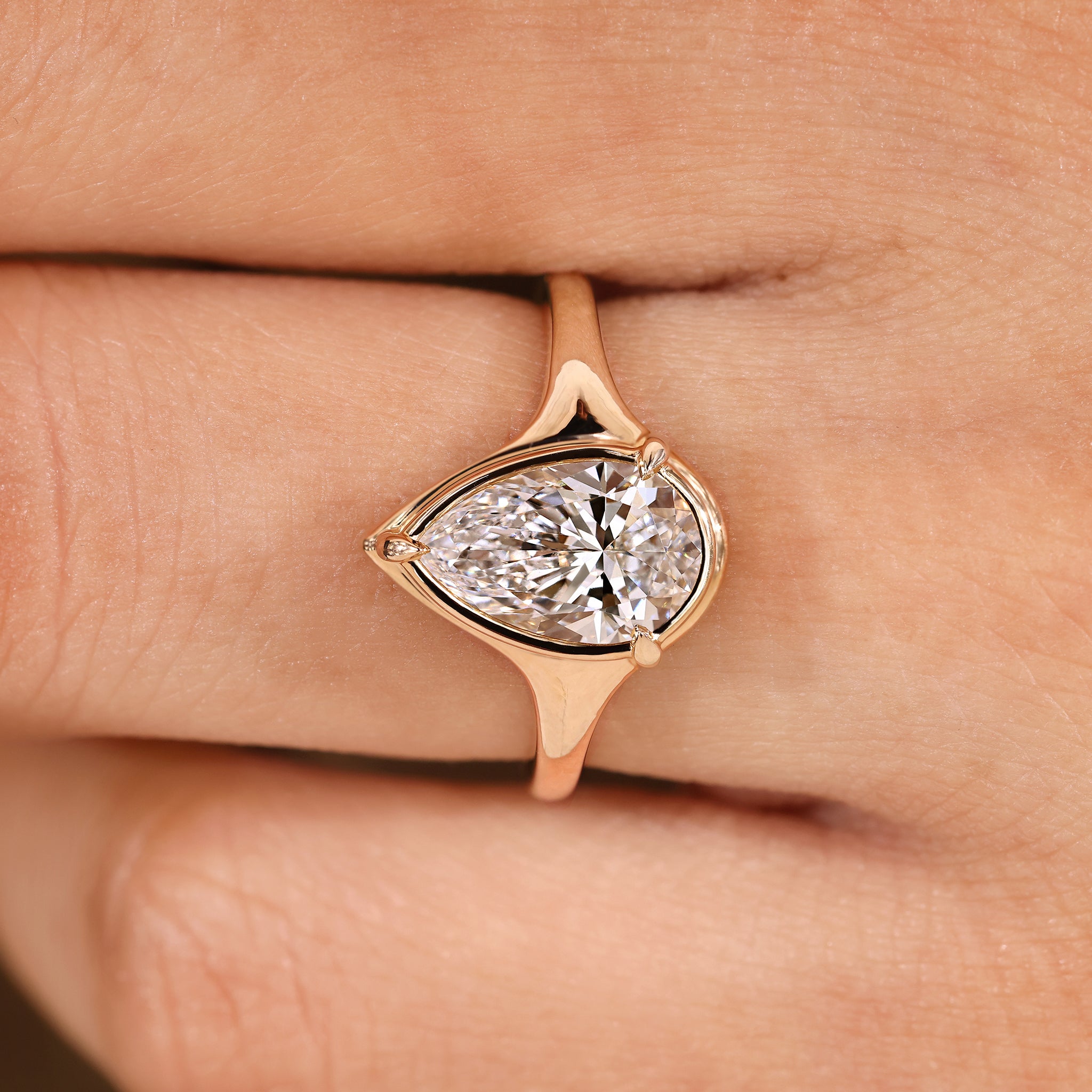 Lab grown pear cut diamond engagement ring with bezel.
