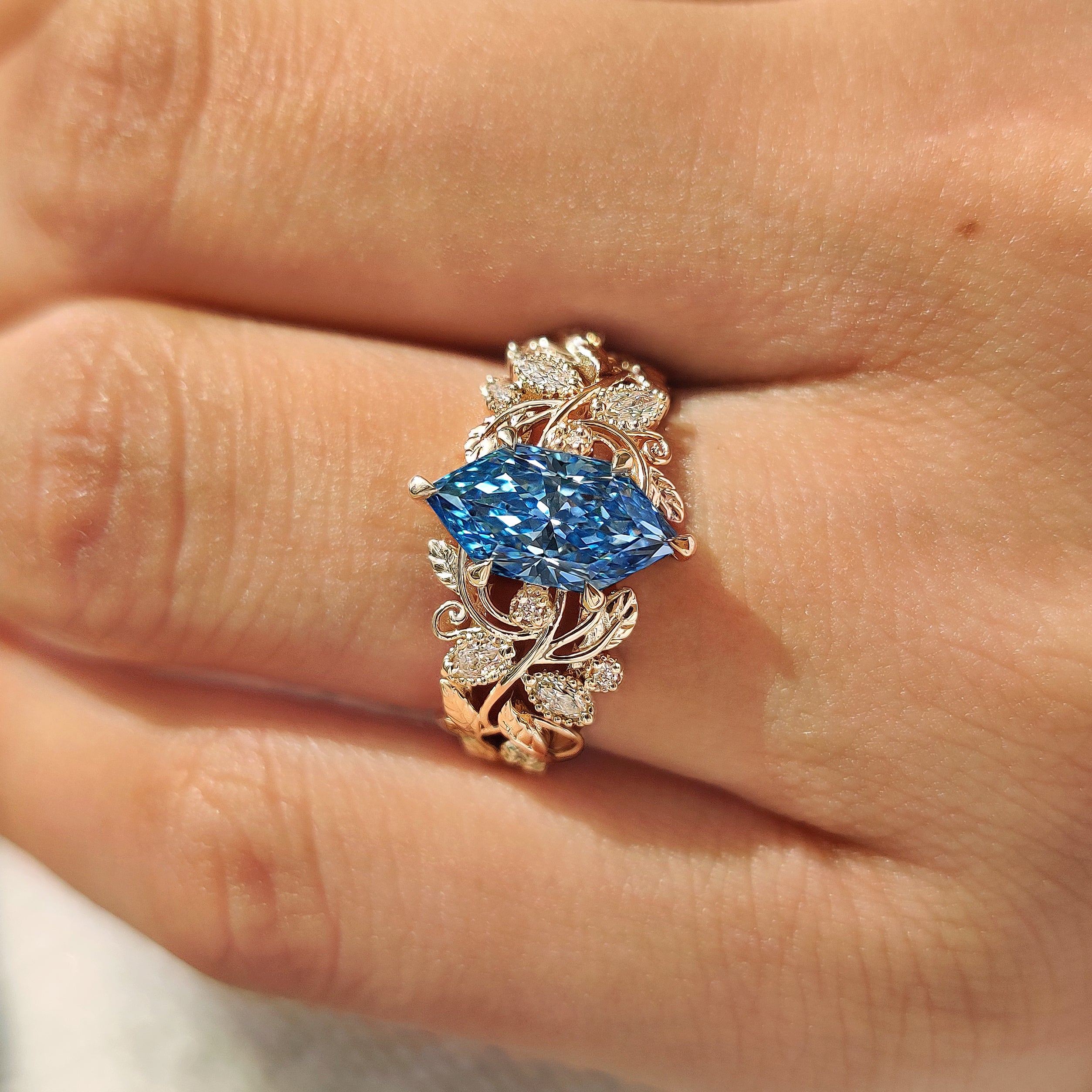 Leaf and vine engagement ring with blue marquise diamond
